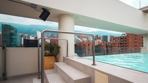 A rooftop pool area with a view of a cityscape and mountains in the background. - Sites Hotel (Medellín)