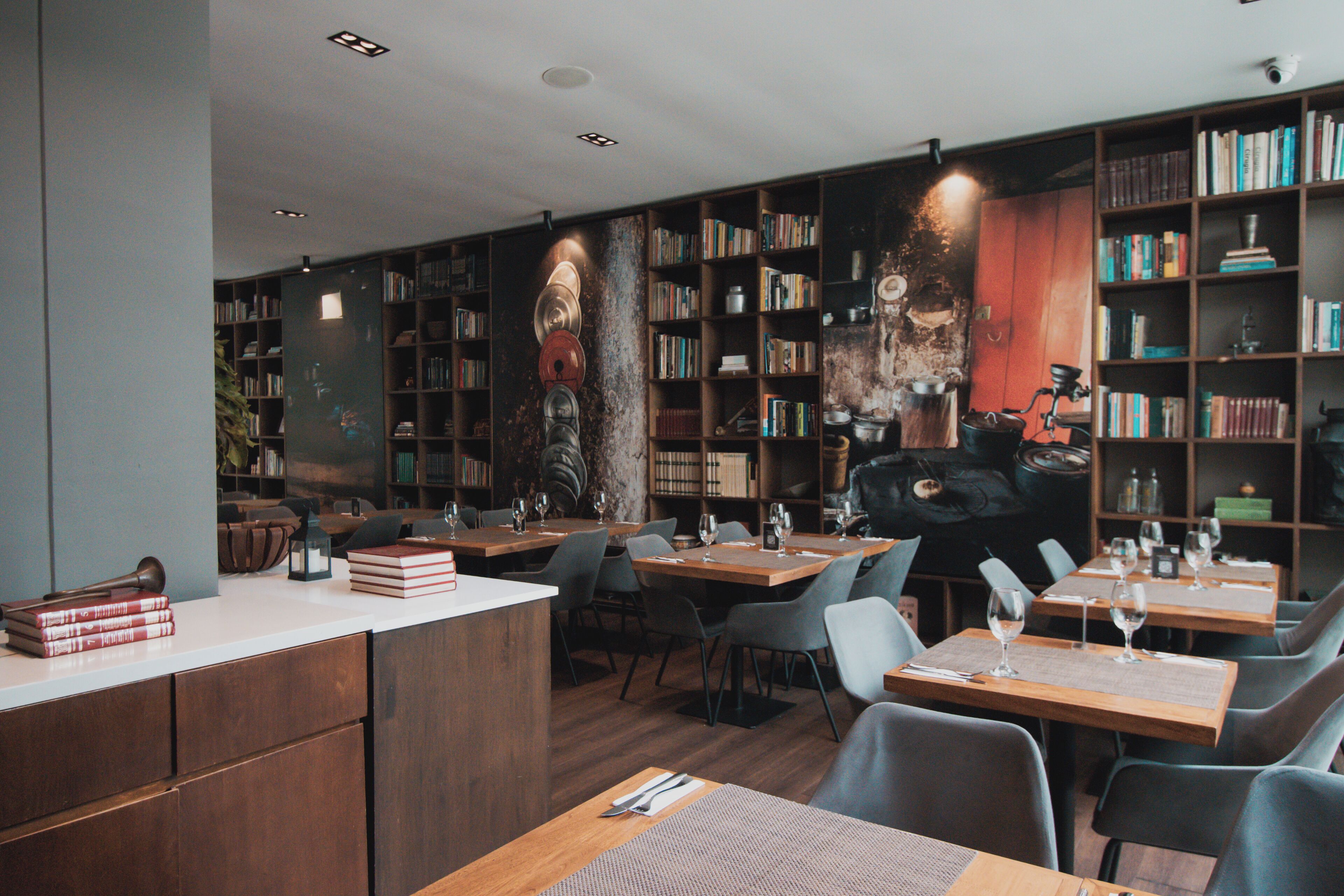 A restaurant with wooden tables and chairs, bookshelves, and a rustic decor.
