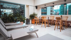 A rooftop terrace with lounge chairs, wooden tables, and potted plants. - Sites Hotel (Medellín)