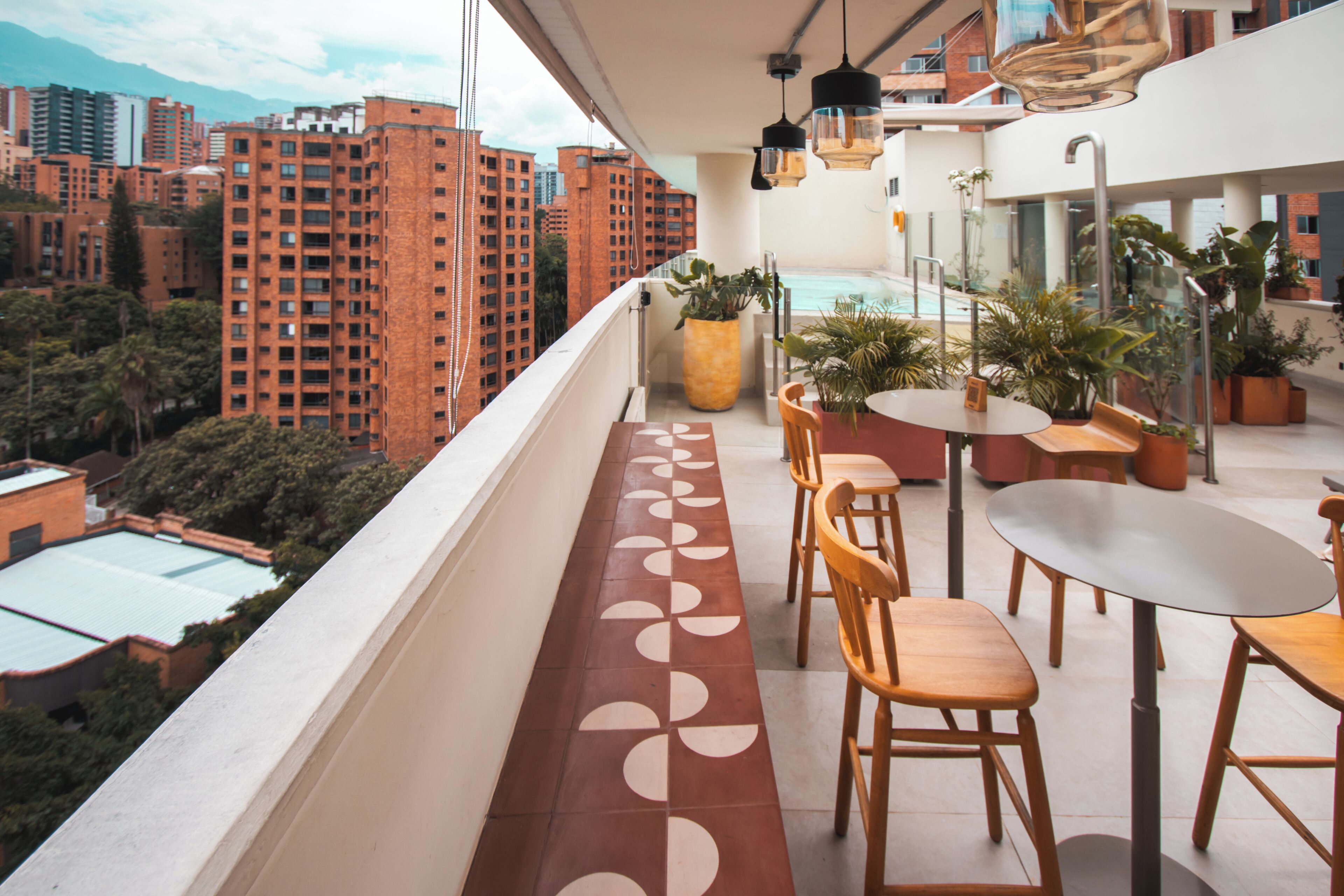 A balcony with a pool, wooden chairs, and potted plants.