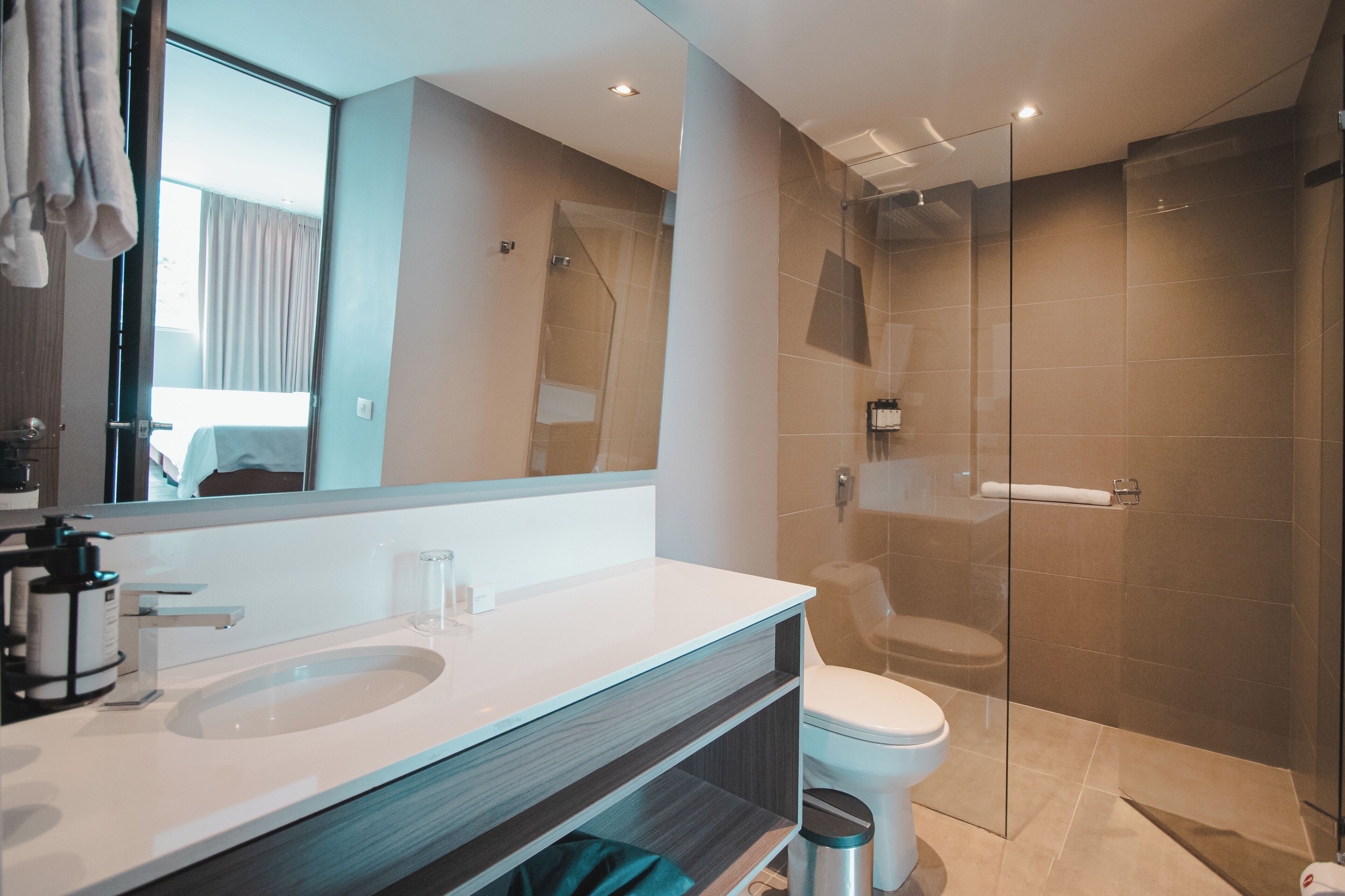Un baño moderno con ducha de vidrio, lavamanos blanco y un inodoro.