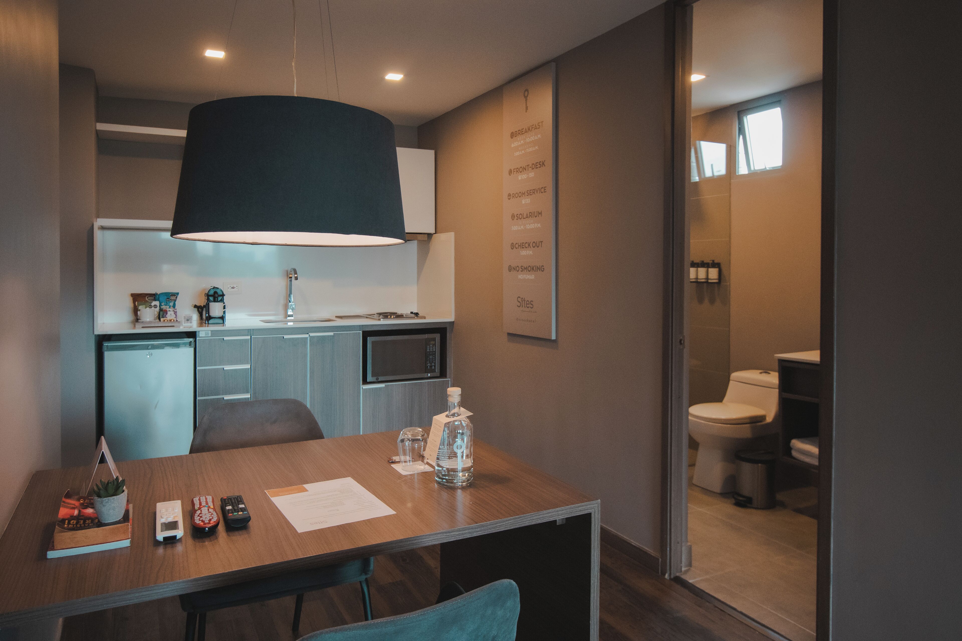 Una habitación de hotel moderna con comedor, kitchenette y baño.