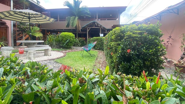 A courtyard with a seating area, a hammock, and a variety of plants. - Hostel La Choza Inn (La Fortuna)
