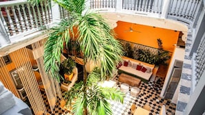 A multi-level atrium with a checkered floor, a central seating area with a sofa and cushions, and several potted plants.