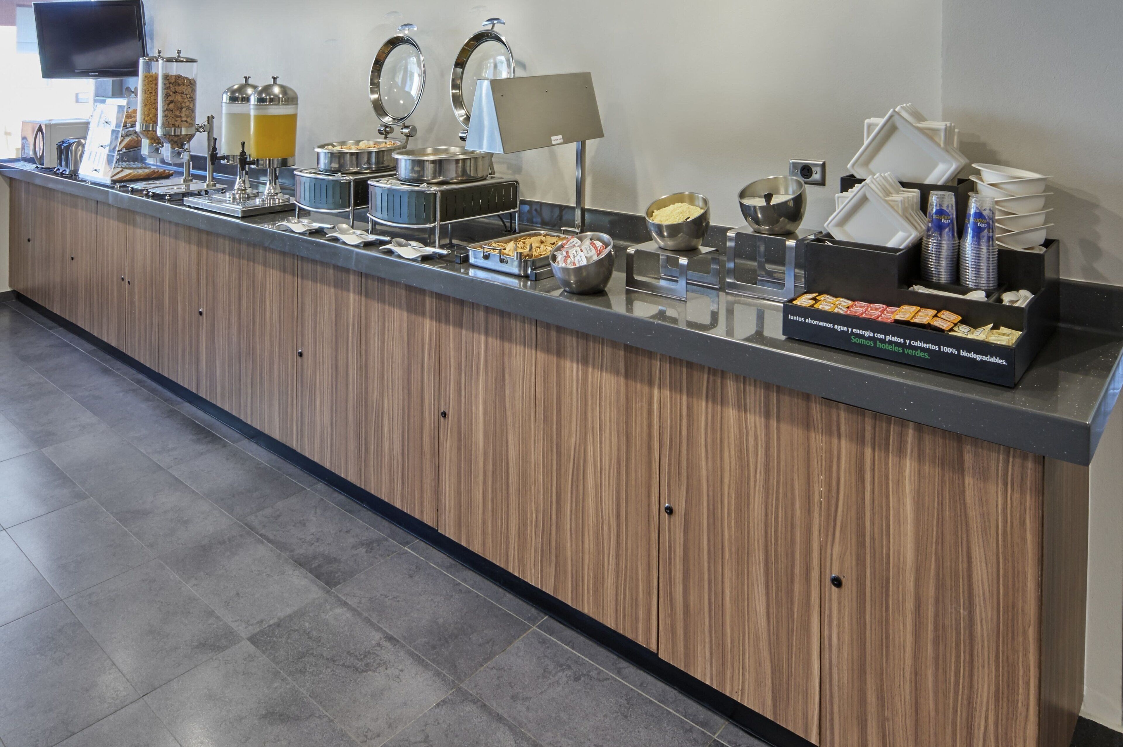 Un comptoir de buffet avec différents distributeurs de nourriture et de boissons, notamment une machine à café et un distributeur de jus.