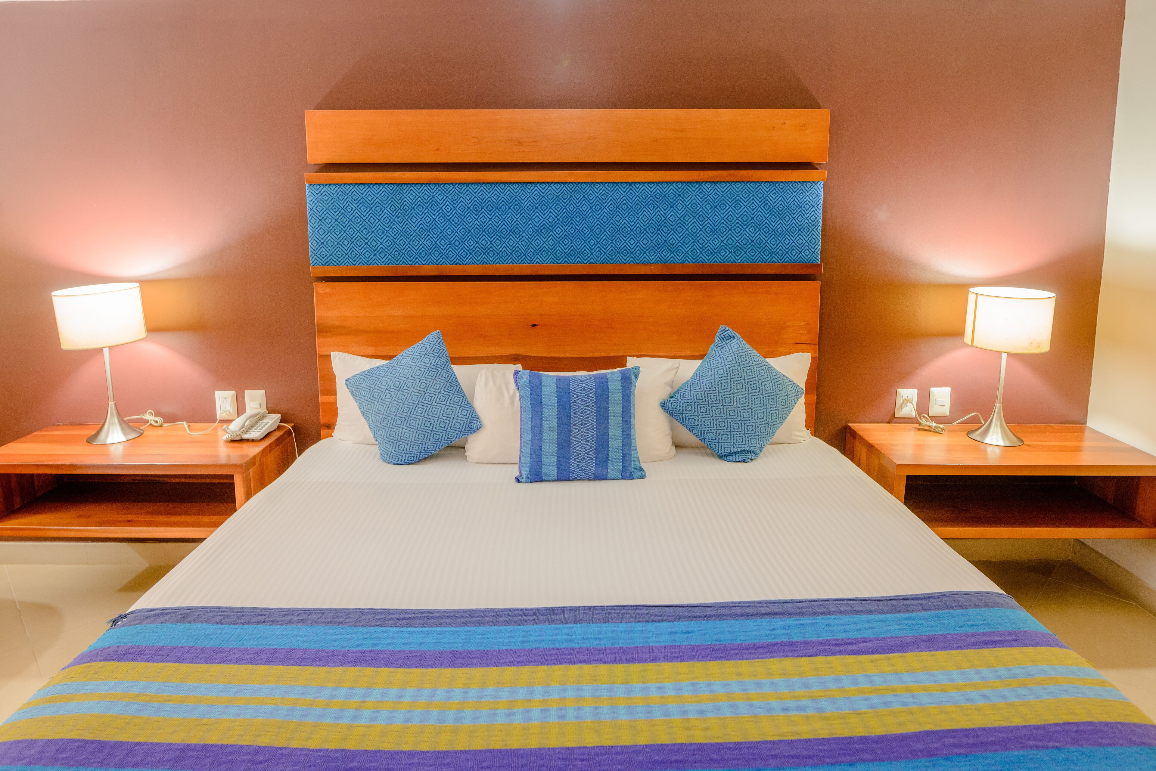 A hotel room with a large bed, two bedside tables with lamps, and a wooden headboard.