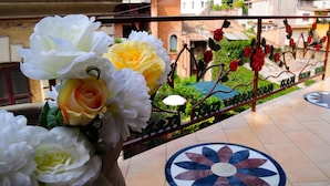 A balcony with a flower arrangement, a metal railing, and a tiled floor with a circular pattern. - Little Rhome Suites (Rome)