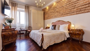 A bedroom with a large bed, wooden furniture, a stone wall, and a chandelier. - Little Rhome Suites (Rome)