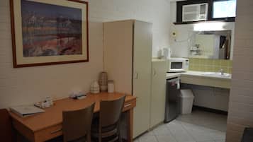 Uma cozinha compacta com uma mesa de madeira, cadeiras, geladeira, micro-ondas e pia.