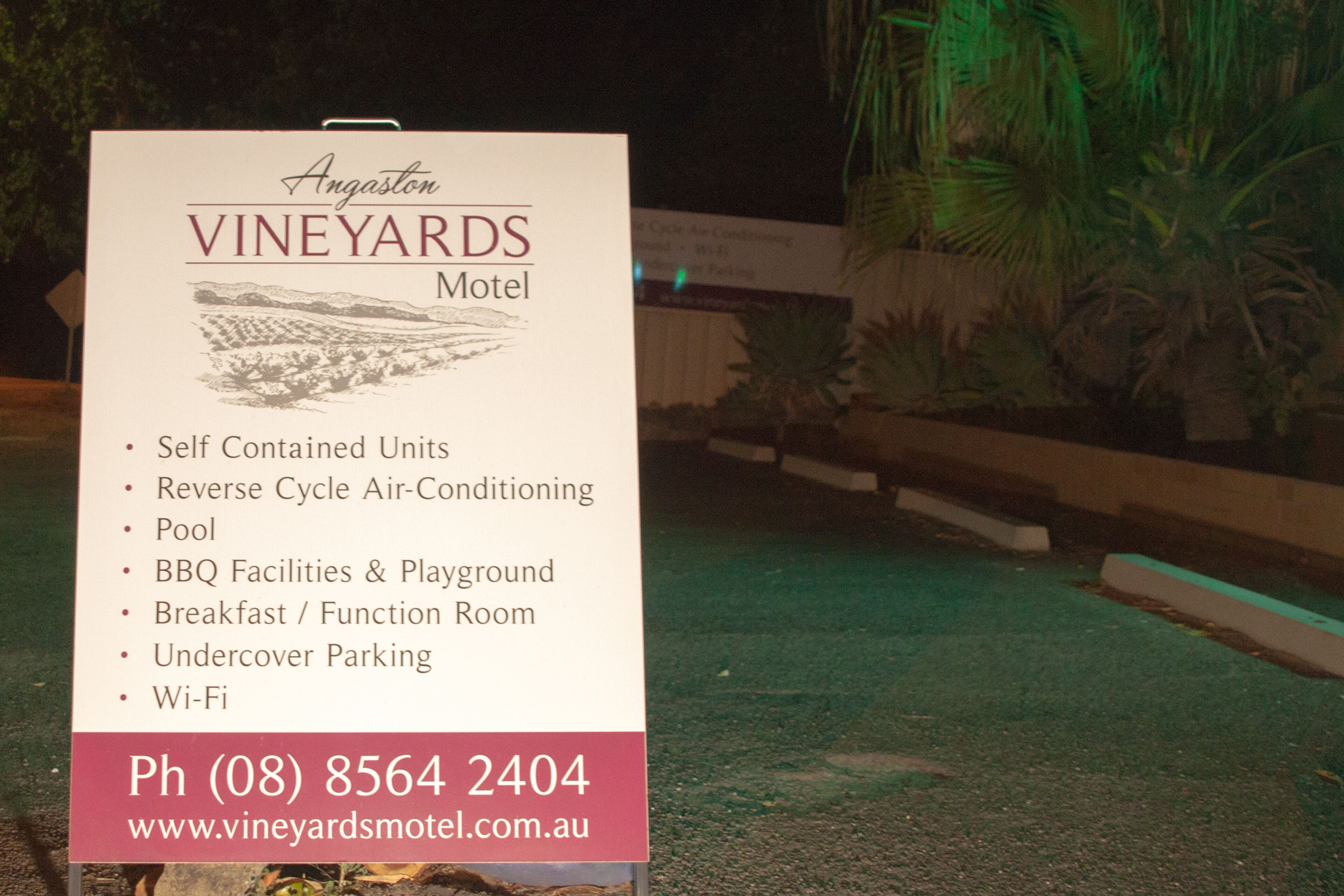 A sign for Angaston Vineyards Motel listing amenities like self-contained units, reverse cycle air-conditioning, pool, BBQ facilities, and Wi-Fi.