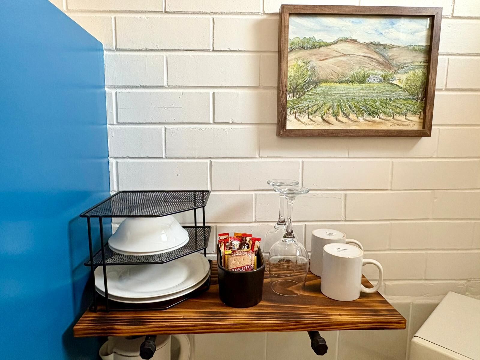 A kitchen counter with a wine glass, a coffee mug, and a container of snacks.