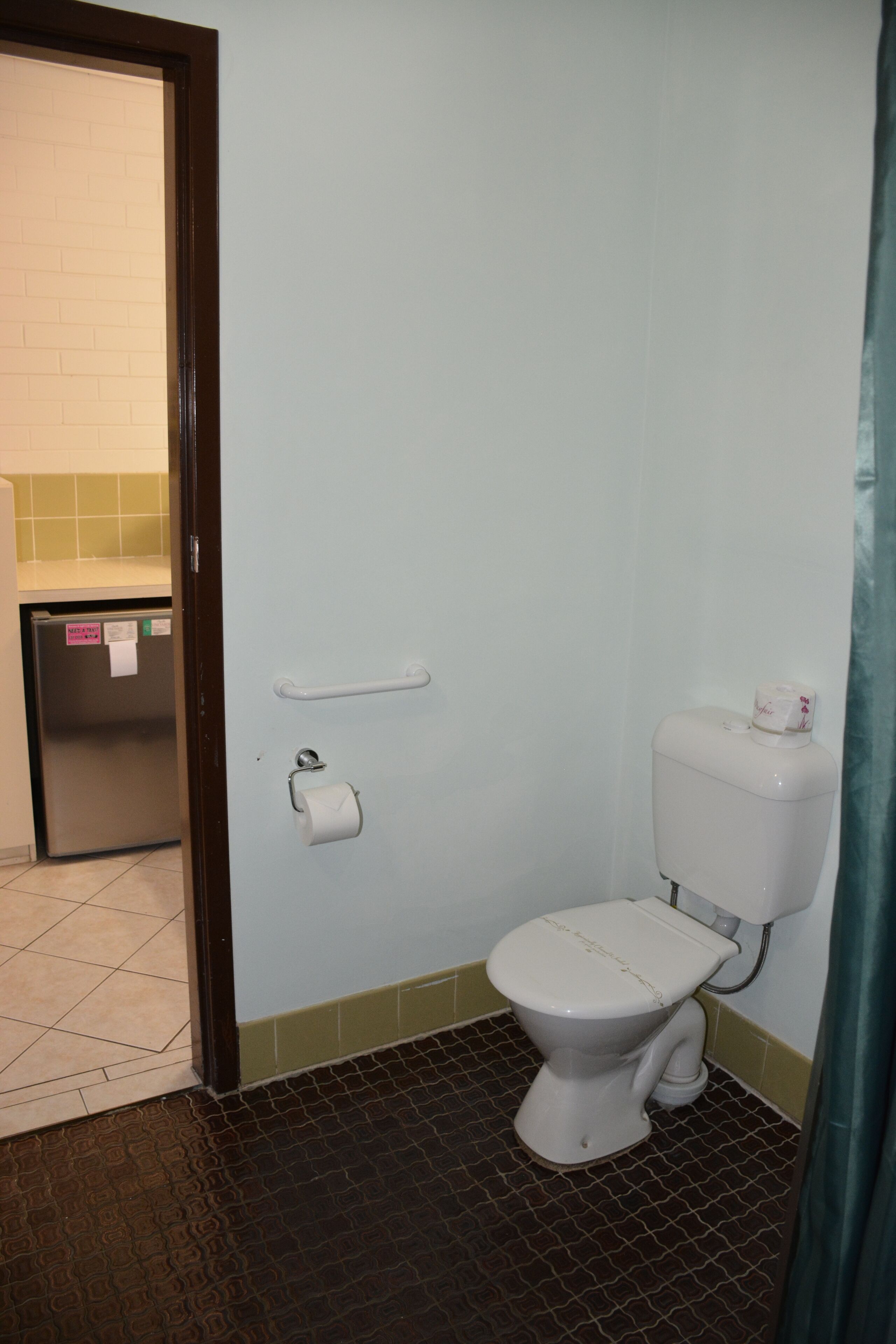 A small bathroom with a toilet, a paper towel holder, and a trash bin.