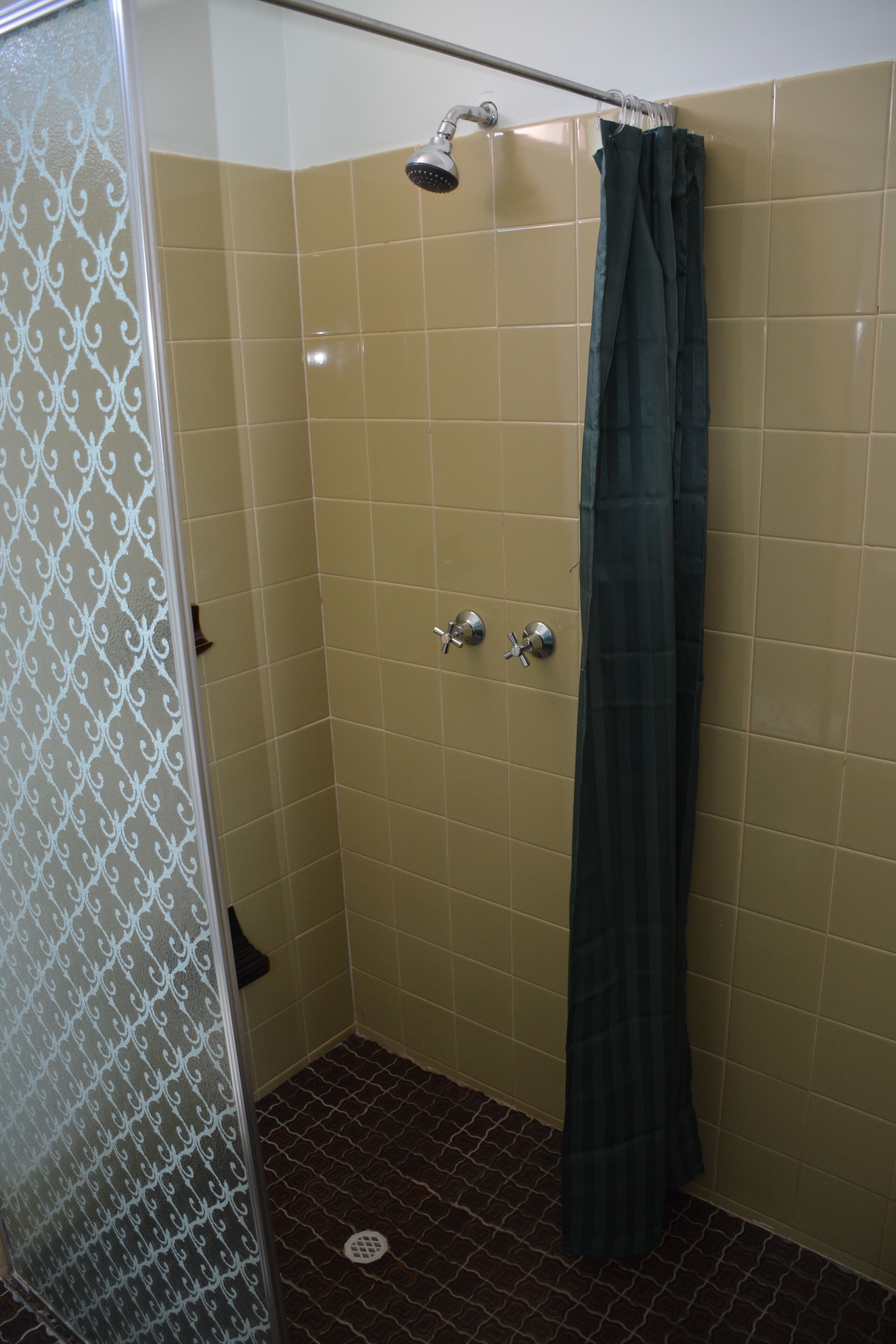 A small, enclosed shower area with a showerhead, a towel rack, and a shower curtain.