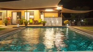 Una piscina con zona de patio, incluyendo sillas y plantas en macetas.
