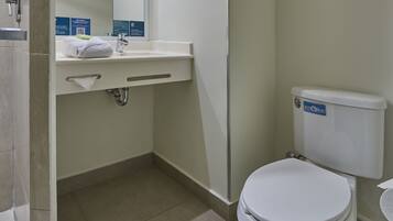 A bathroom with a toilet, sink, and mirror.
