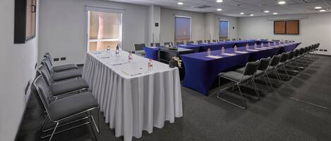 A conference room with a long table, chairs, and a projector screen.