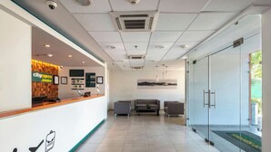 Un área de recepción con mostrador, asientos y puerta de vidrio que da al exterior.