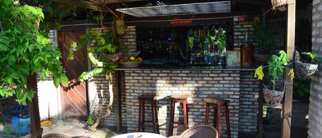 An outdoor bar area with a brick wall, wicker chairs, and a table.