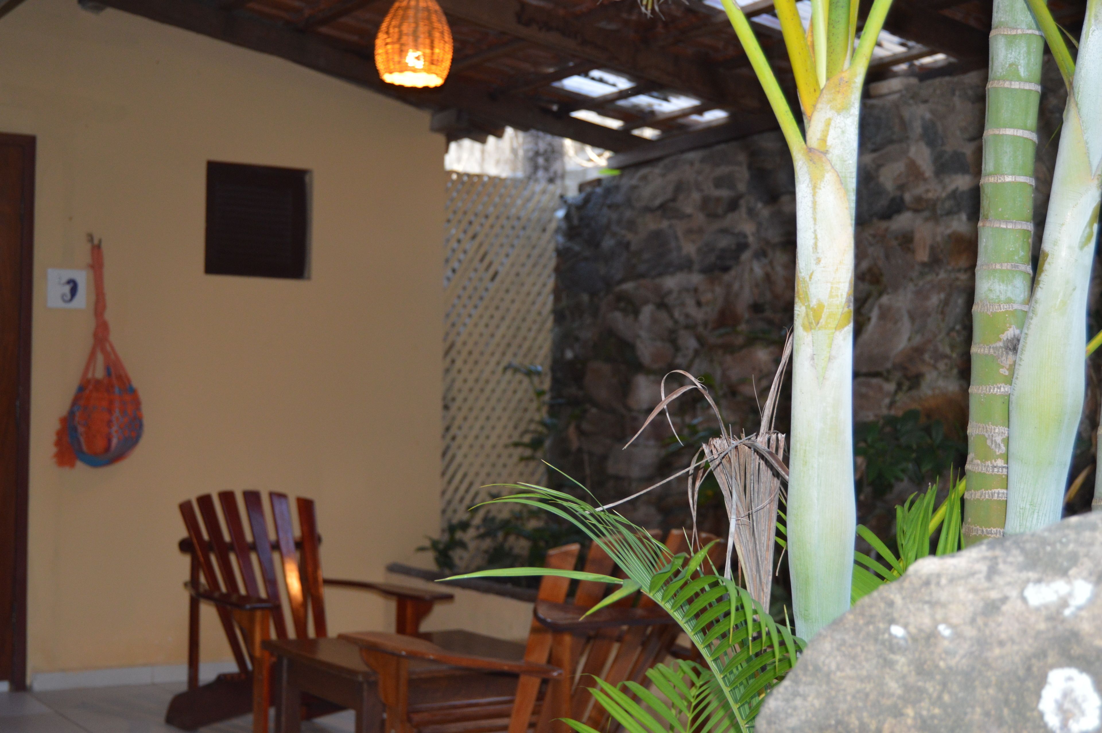 A wooden table and chairs in a room with a stone wall and a hanging light fixture.