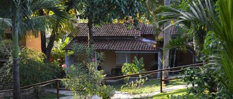 A house with a tiled roof, surrounded by lush greenery and palm trees.