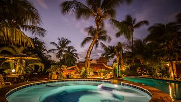 Relax by the serene pool surrounded by lush palm trees and a cozy lounge area.