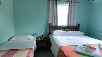 Una habitación con dos camas individuales, una mesita de noche con lámpara y una ventana con cortinas.