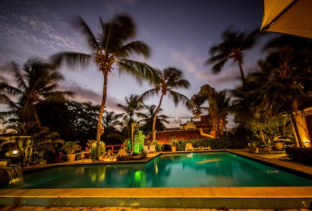 Una piscina al aire libre, sombrillas, sillones reclinables de piscina