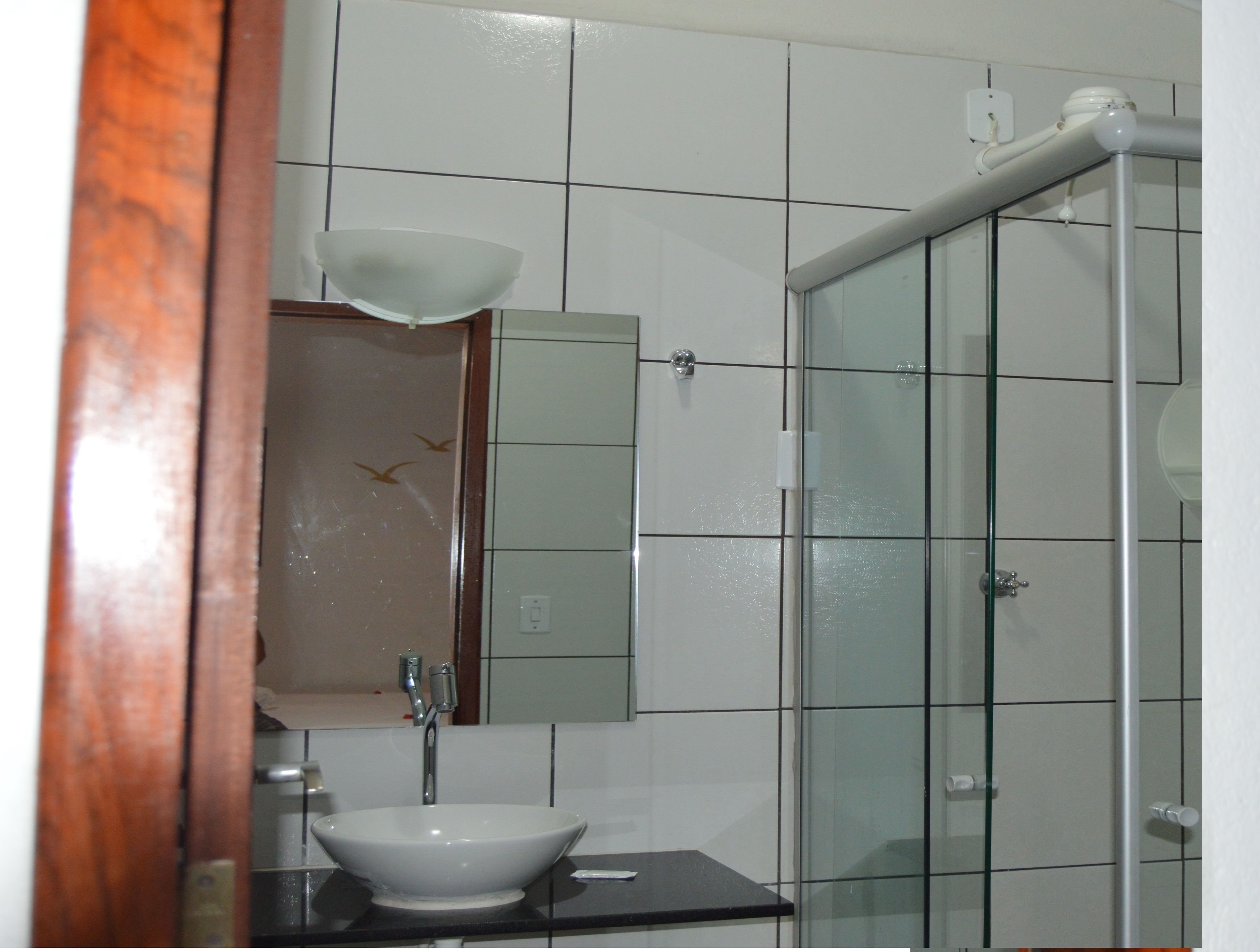 Une salle de bain avec un lavabo blanc, un miroir et une cabine de douche en verre.
