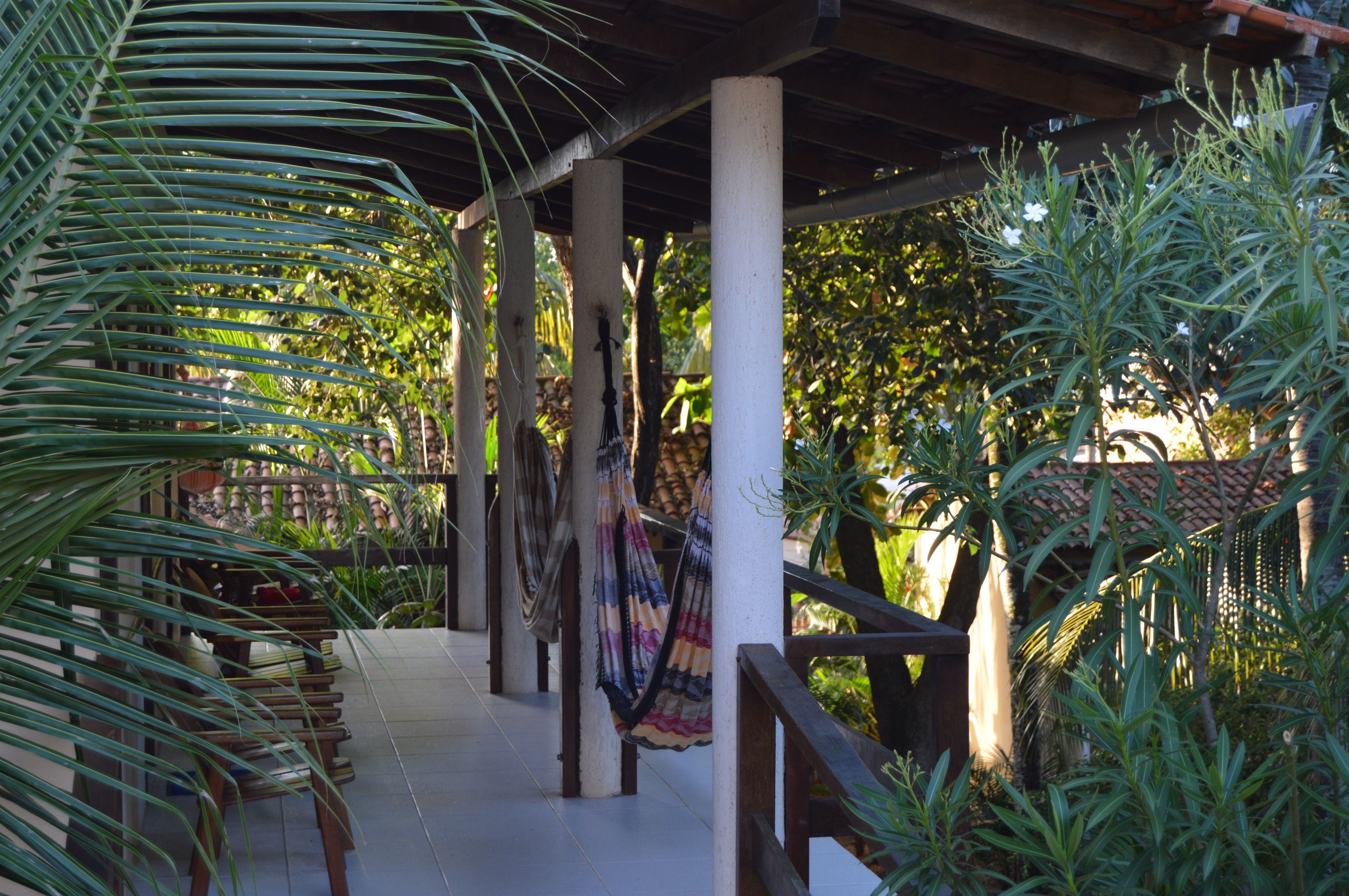 A covered outdoor area with wooden chairs and a hammock.