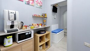 A kitchenette with a coffee maker, microwave, toaster, and shelves with food items. - Domus Domas & Boutique   (Rome)