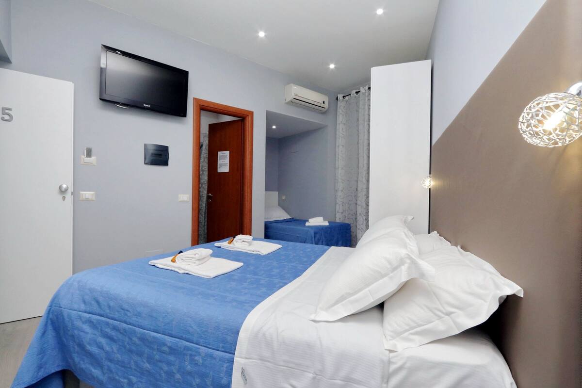 Ein Hotelzimmer mit Bett, Fernseher, Klimaanlage und Duschbereich.