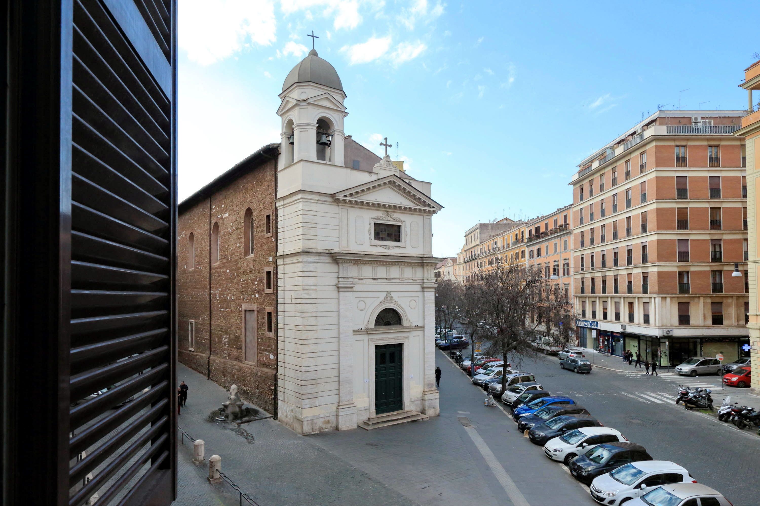 A church with a bell tower and a parking lot with cars.