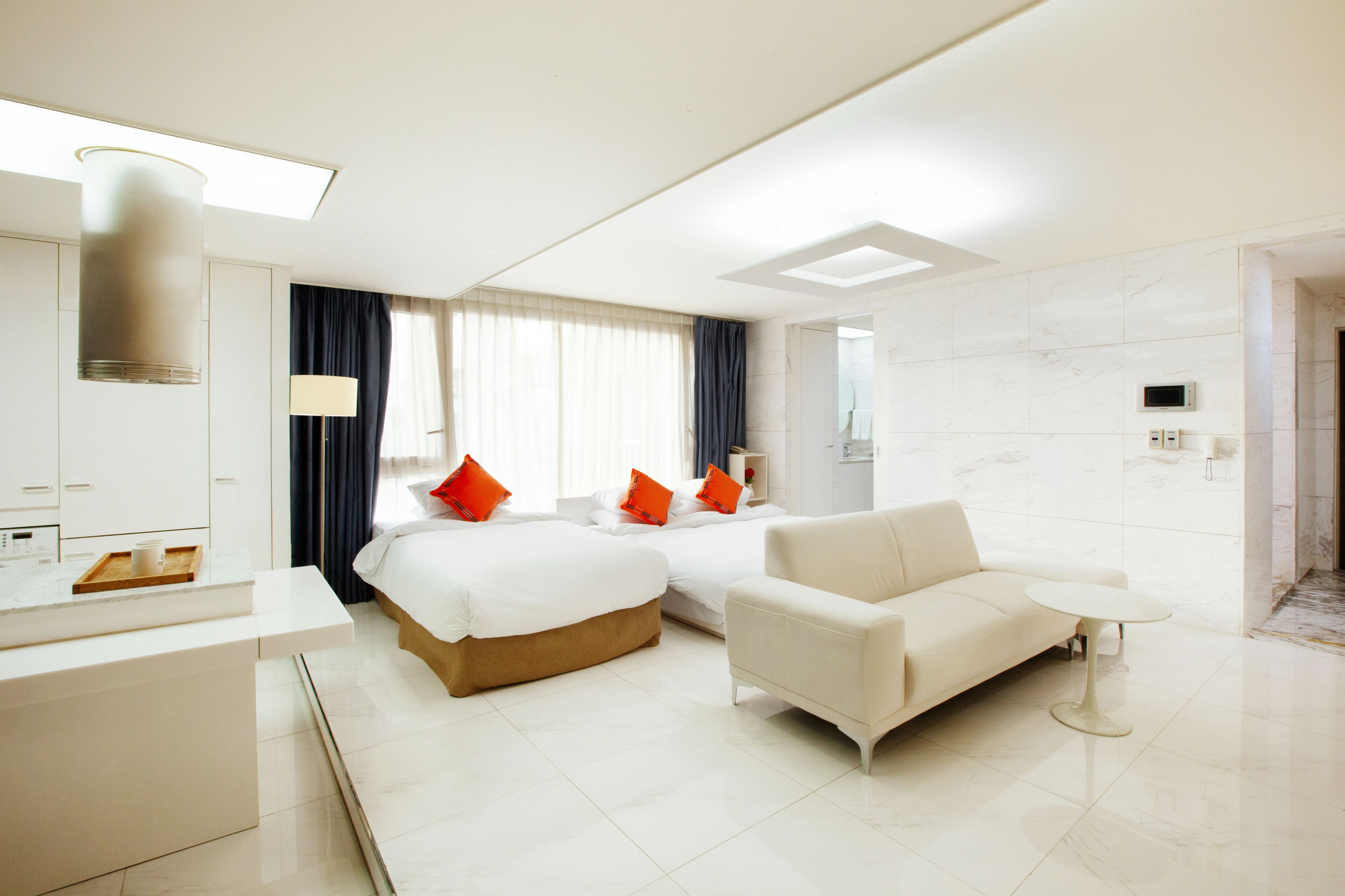 Une chambre d’hôtel moderne avec deux lits, un canapé, une petite table et un bureau.