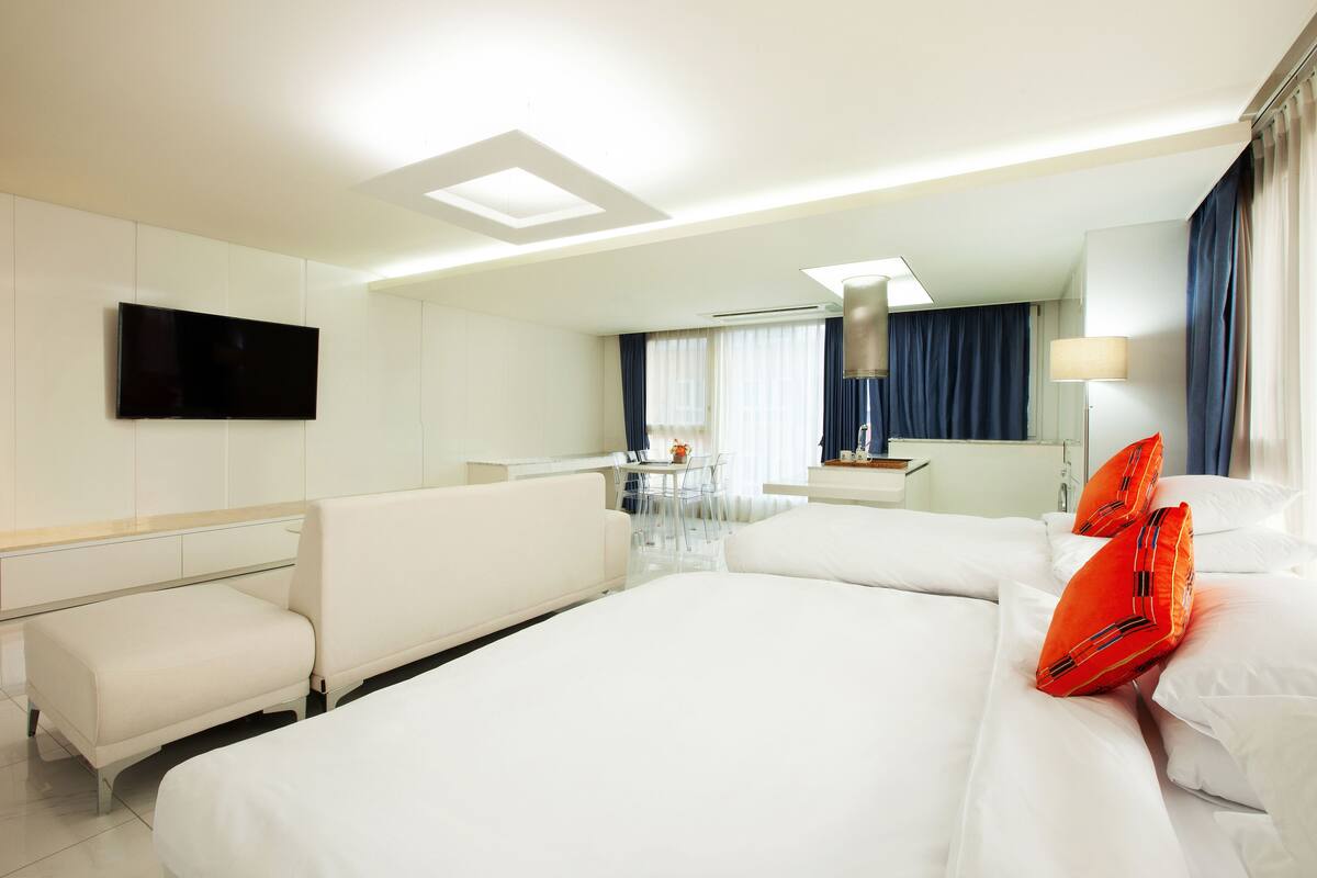 A hotel room with a large bed, a desk, a chair, and a TV mounted on the wall.