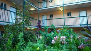 A multi-story building with balconies and a garden area with various plants and flowers. - Alatai Holiday Apartments (Darwin)