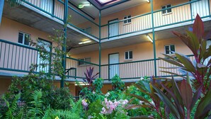 A multi-story building with balconies, surrounded by lush greenery and various plants. - Alatai Holiday Apartments (Darwin)
