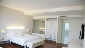 Une chambre d’hôtel moderne avec un grand lit, une table de chevet, un bureau et un miroir.