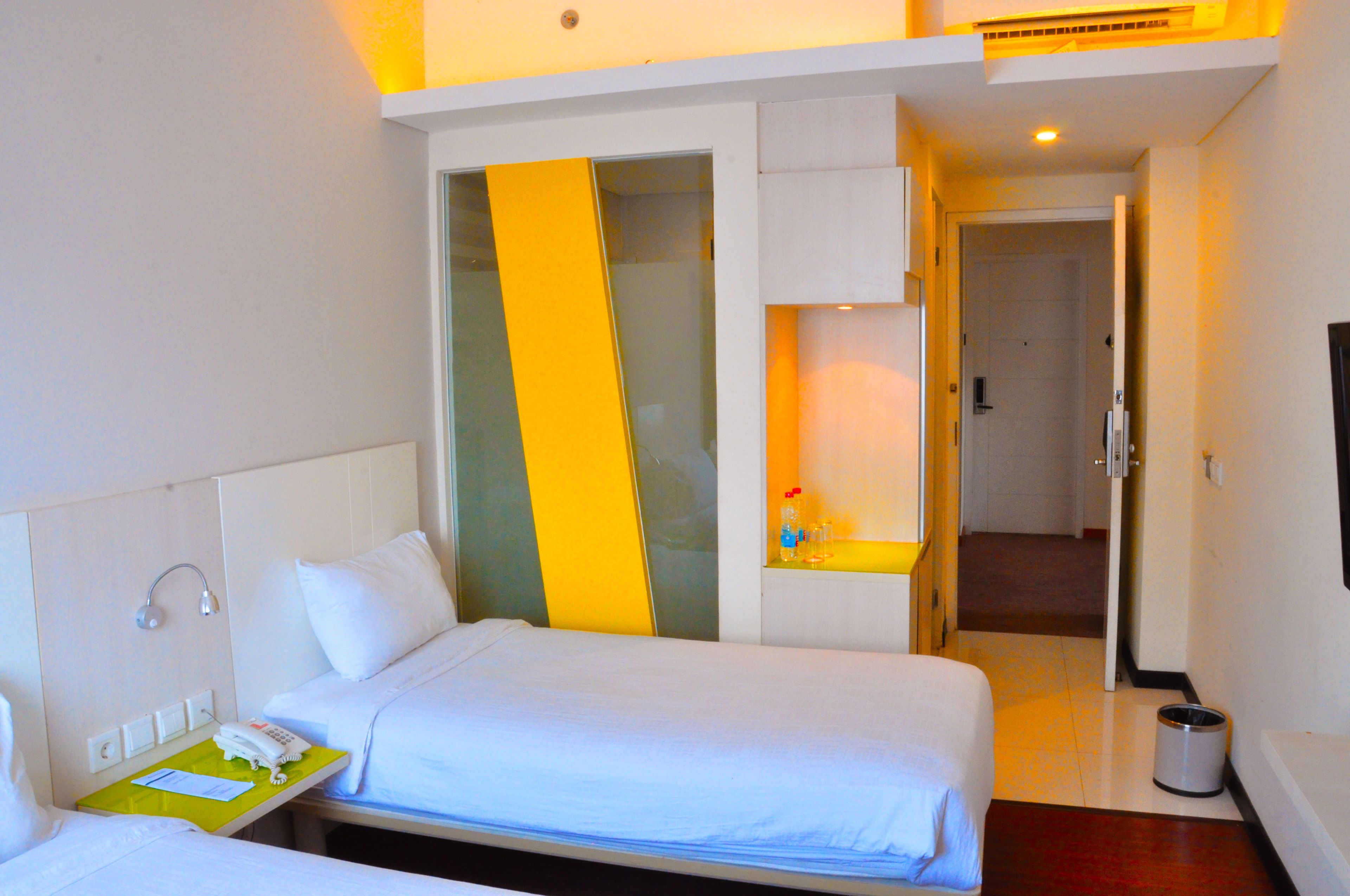 Una habitación de hotel con dos camas, un baño y una pequeña zona de estar.
