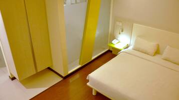 A hotel room with a bed, a nightstand with a lamp, and a wardrobe.