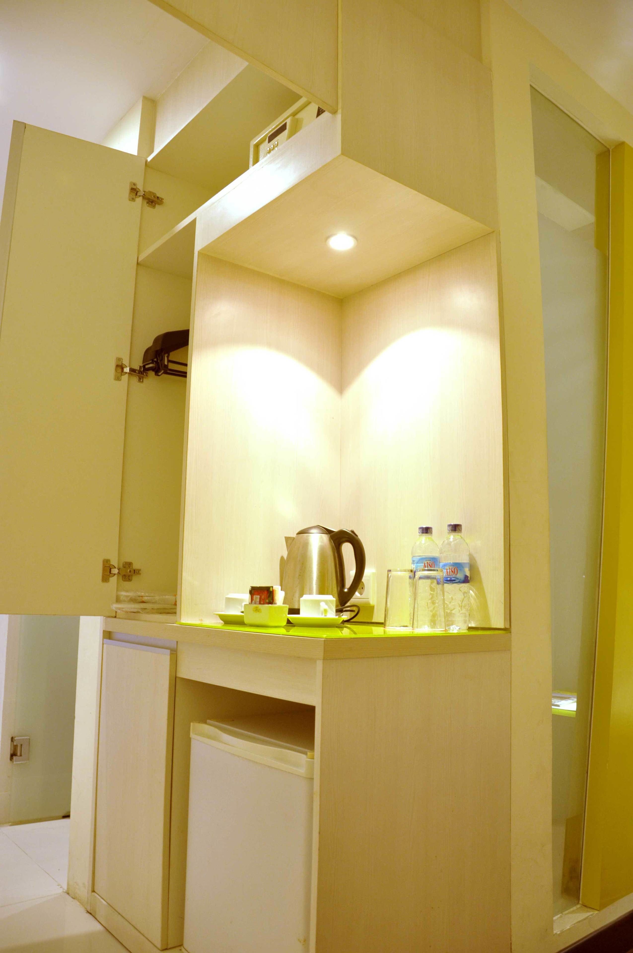 A corner of a room with a built-in shelf, a mirror, and a small refrigerator.