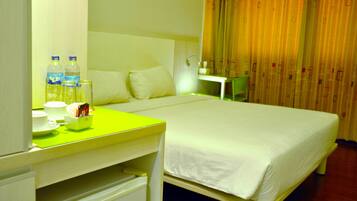 A hotel room with a bed, a desk with a chair, a nightstand, and a mirror.