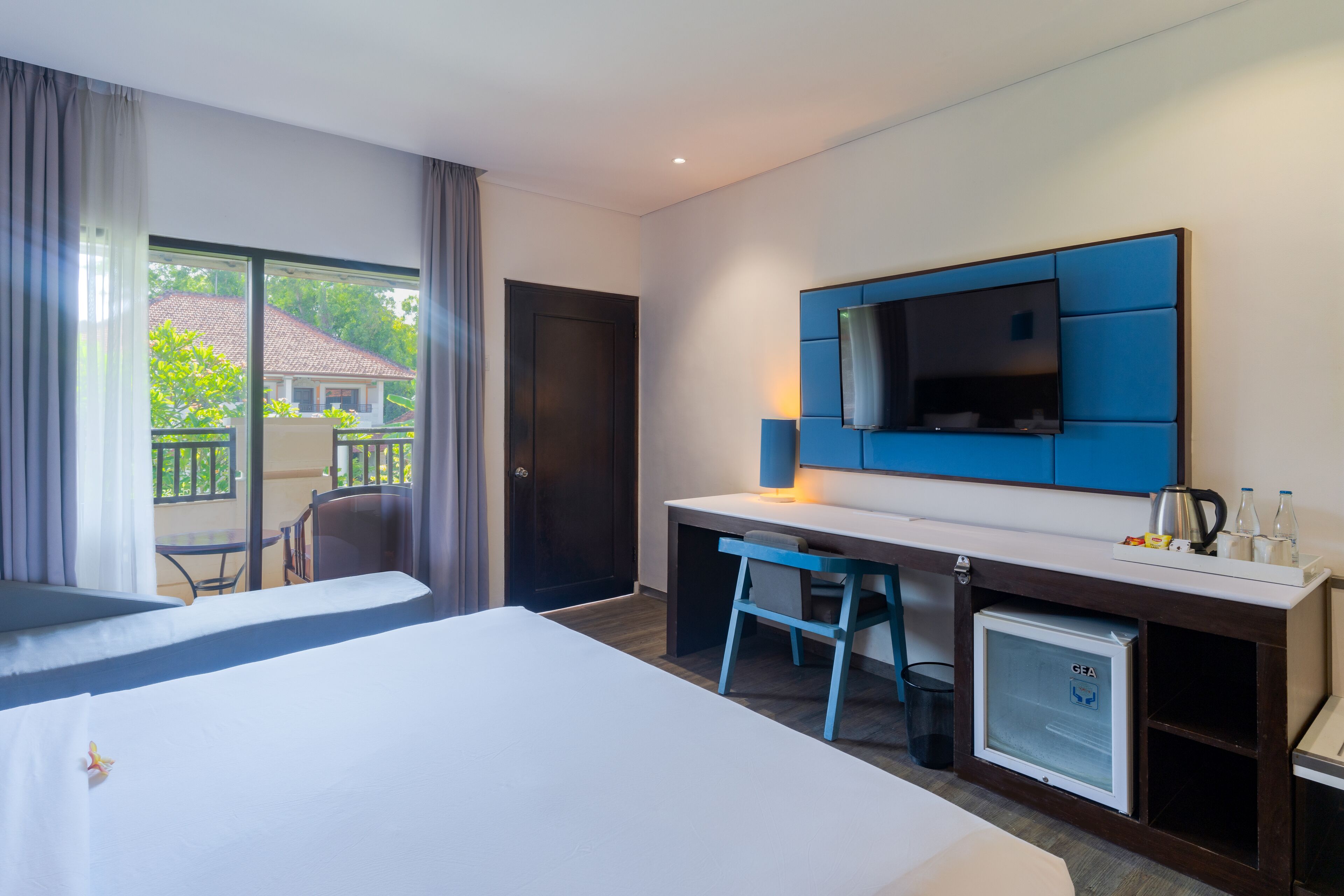 Een hotelkamer met een bed, een bureau, een stoel, een televisie en een minibar.