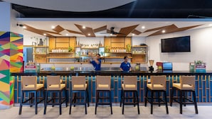 Eine Bar mit einer Theke, Barhocker und Flaschenregalen.
