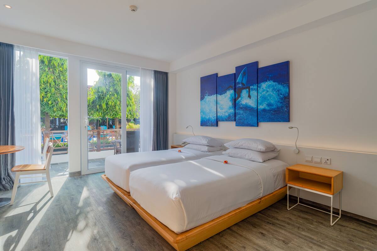 Une chambre d’hôtel moderne avec un grand lit, une table de chevet en bois et une vue sur l’extérieur.