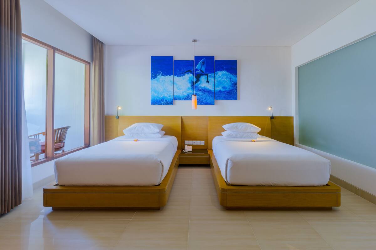 Une chambre d’hôtel avec deux lits, une grande fenêtre et une œuvre d’art accrochée au mur.