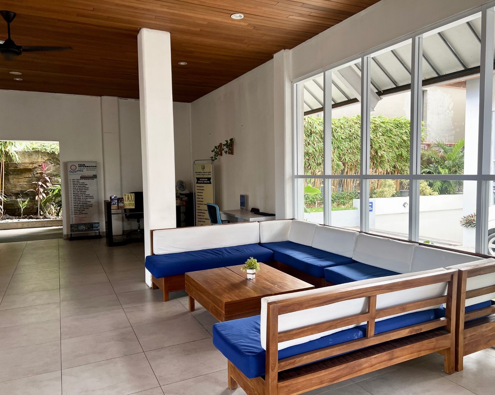 A modern hotel lobby with a large seating area, a reception desk, and a view of the outdoors.