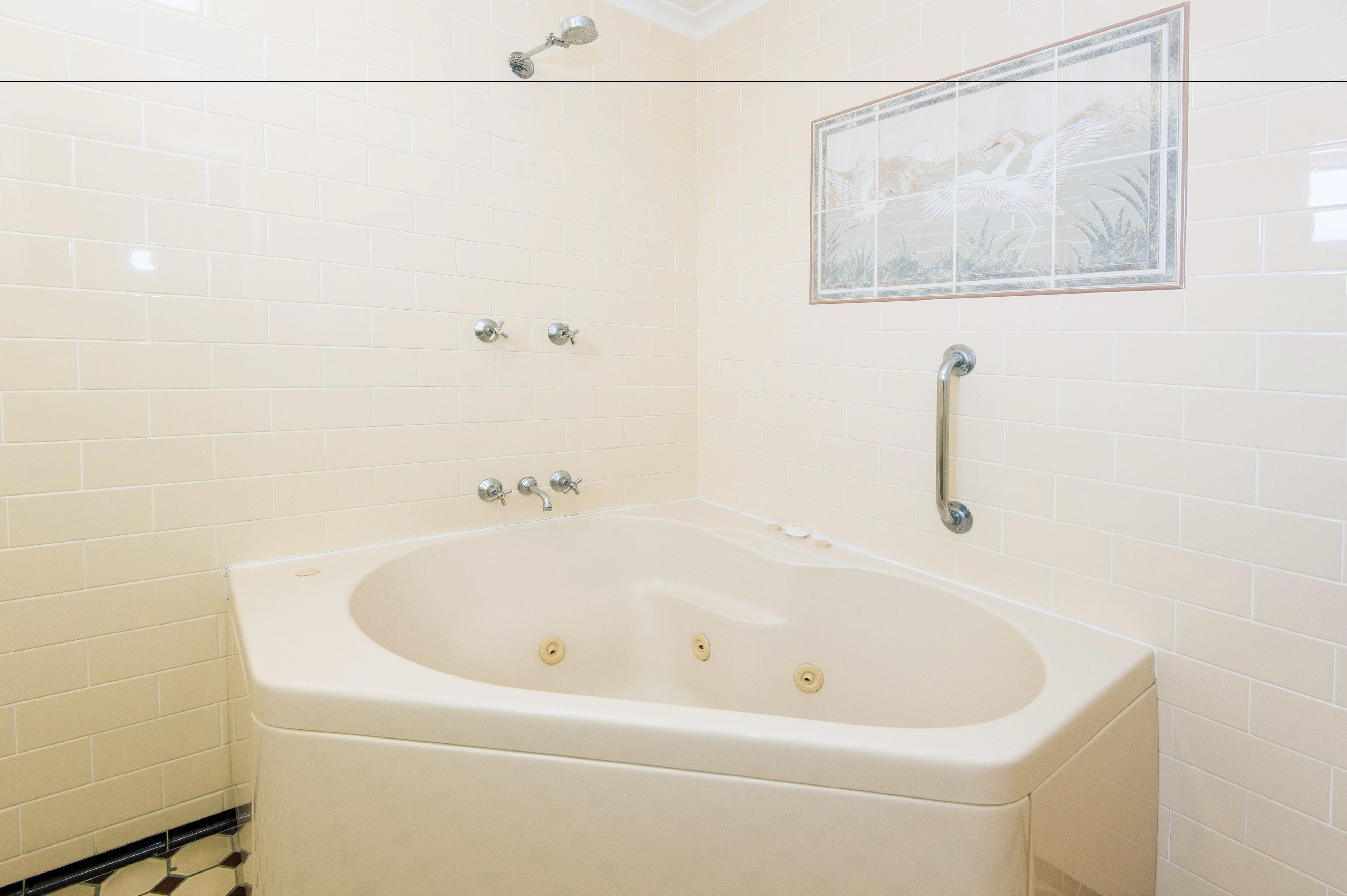 A bathroom with a bathtub, a showerhead, and a framed artwork on the wall.