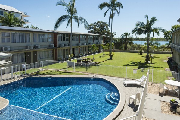 A hotel with a swimming pool, lounge chairs, and a view of the water.
