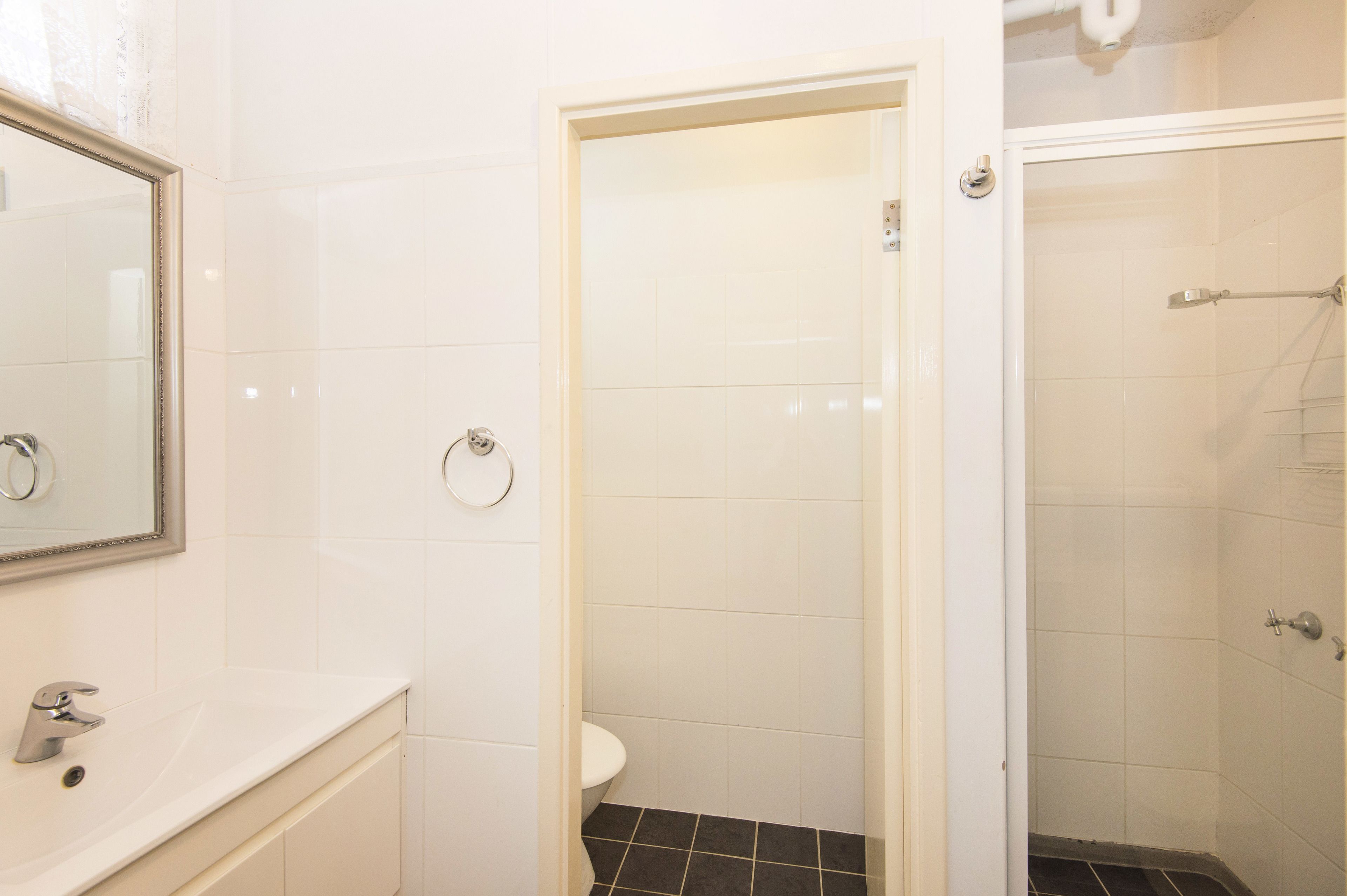 Une salle de bain avec un lavabo blanc, des toilettes et un espace douche.