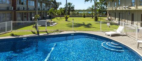 Una piscina al aire libre, sillones reclinables de piscina